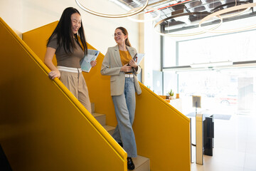 Colleagues walking down bright yellow office staircase