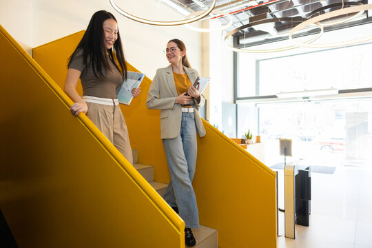 Colleagues walking down bright yellow office staircase