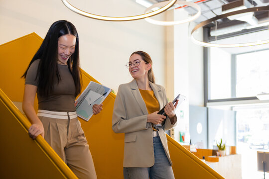 Colleagues walking down stairs in modern office