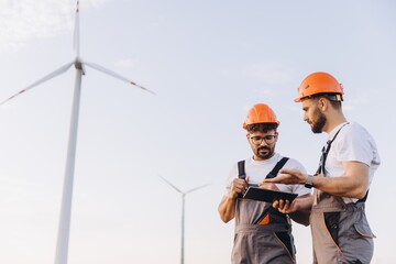 Engineers using digital tablet working on wind turbine farm
