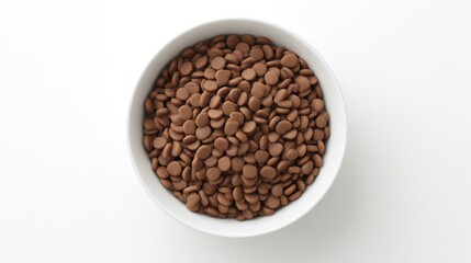 Fototapeta premium Bowl filled with round chocolate chips, showcasing a rich brown color and smooth texture, placed on a clean white surface, ideal for baking and dessert recipes