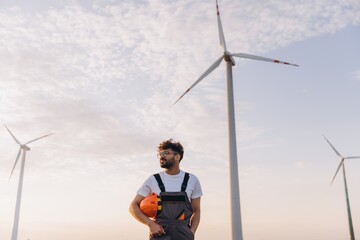Arab engineer holding helmet inspecting wind turbines in the desert