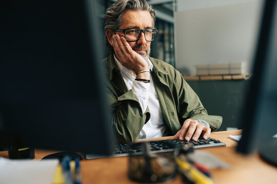 Bored senior businessman working on desktop PC at office