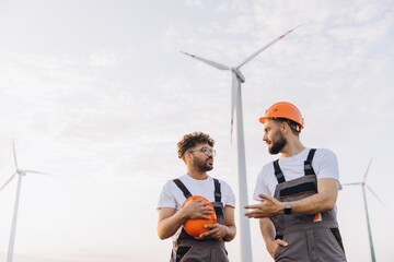Engineers discussing next to wind turbines in a wind farm