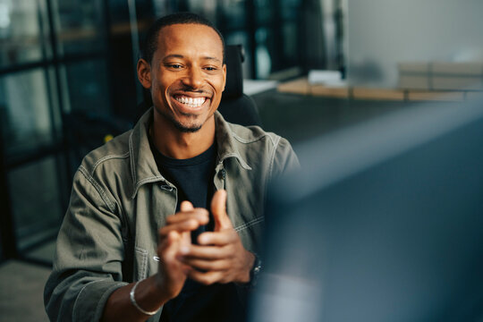 Happy businessman clapping while looking at computer monitor at office