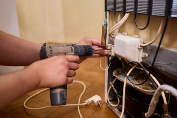 Fixing Appliances Using a Power Drill Inside a Refrigerator for Repair and Maintenance Tasks