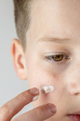 teenage boy applying acne cream, Teen boy focused on facial skincare, highlighting self-image...