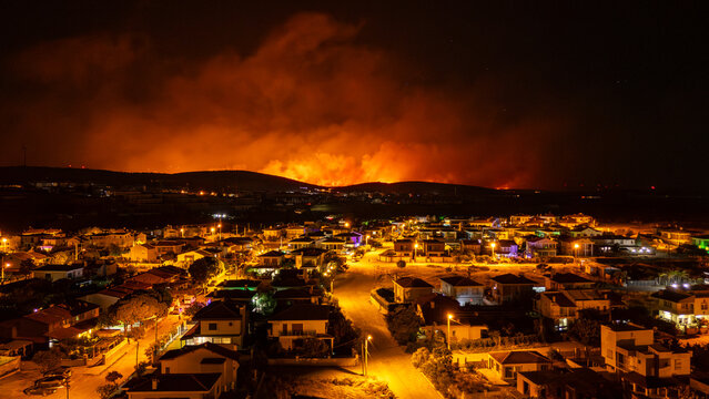 Wildfire burning near Cesme, Turkey, threatening residential area at night