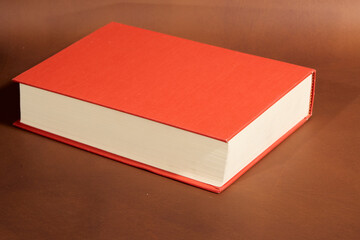 Detail of a Book with Red Cover and Cream Pages on Brown Background
