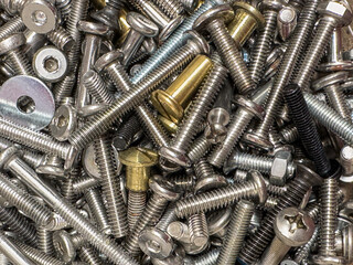 Close-up view of assorted metal screws and bolts in various sizes and finishes, showcasing...