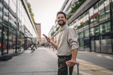 one man with beard and eyeglasses walk with suitcase and use phone