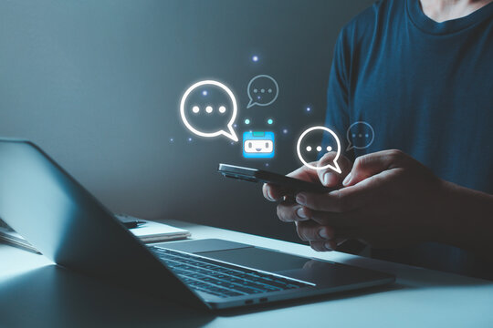 Man using smartphone with chatbot assistant interface for online conversation and AI-powered customer support, with laptop virtual communication icons. Artificial intelligence online business service.