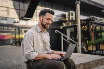 happy satisfied businessman sit on street during break and use laptop