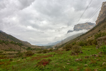  Panoramic view of Baksan gorge in low clouds with power line. September. Weather.