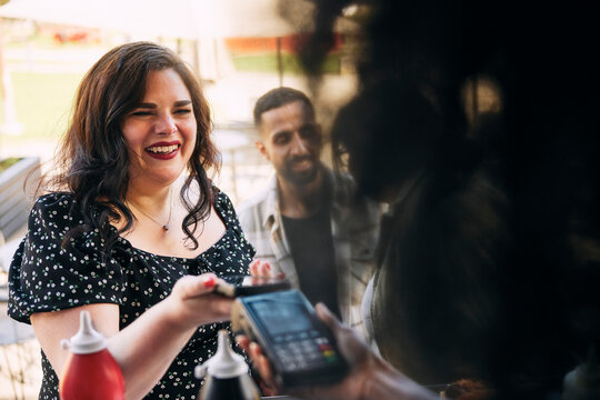 Happy woman making payment through tap to pay method at food truck