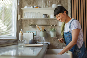 Japanese woman organize kitchen utensils and cutlery in kitchen drawer