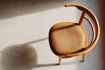 Artistic composition of a minimalist chair with cushion casting an intriguing shadow in an empty space