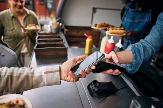 Hand of man paying through smart phone with tap to pay method at food truck