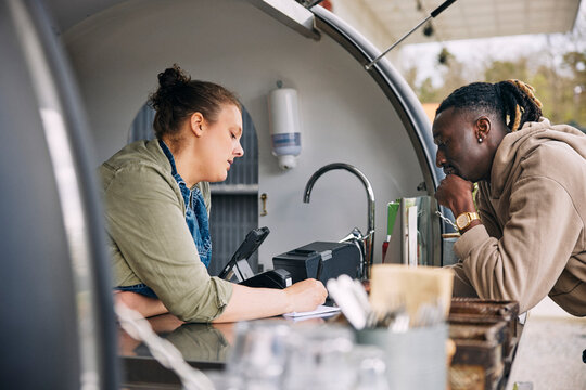 Male and female owner counting orders written on notepad while finishing at food truck