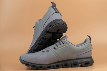 Modern gray athletic shoes displayed against beige background in bright lighting
