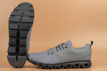 Grey athletic shoes with unique sole design on orange background