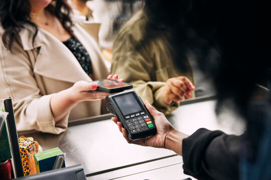Female owner holding credit card reader for woman making payment through tap to pay method at food truck