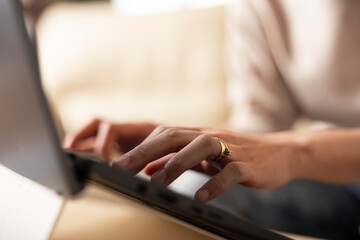 Close up of female hands typing on laptop keyboard, replying to work emails from home. Selective...
