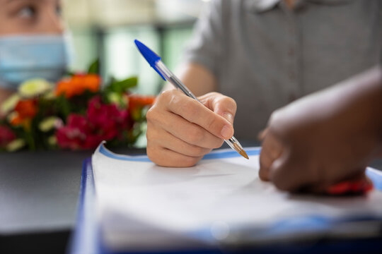 Female staff helps mom and child to visit a family member at facility, ensuring registration forms signing and healthcare protective measures. Assistance at the front desk. Close up. - Powered by Adobe