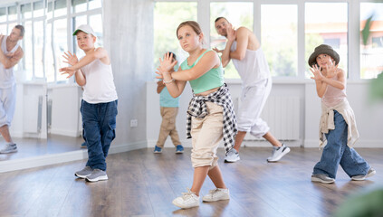 Naklejka premium Positive smiling girl dancing hip hop with group of boys and girls in modern dance class