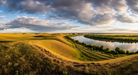 Panoramic landscape view of a river winding through golden fields under a dramatic cloudy sky with sunlight illuminating the scene creating a serene and scenic vista.