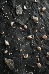 Fototapeta premium Garlic cloves are artfully scattered on a dark textured surface alongside mineral rocks and coarse salt granules, creating a rustic visual appeal