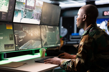 Soldier looking at screens in command center housing operational missile defense system designed to intercept ballistic rockets. Tracking equipment operator using radar systems