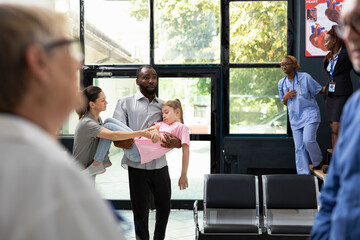 Young kid faints in her father arms with worried mother by her side, as african american team...
