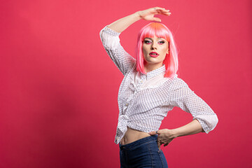 Gorgeous caucasian model with pink hair confidently striking a pose with one hand over head and...