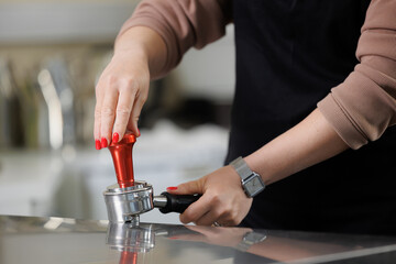 Female barista using tamper in coffee factory