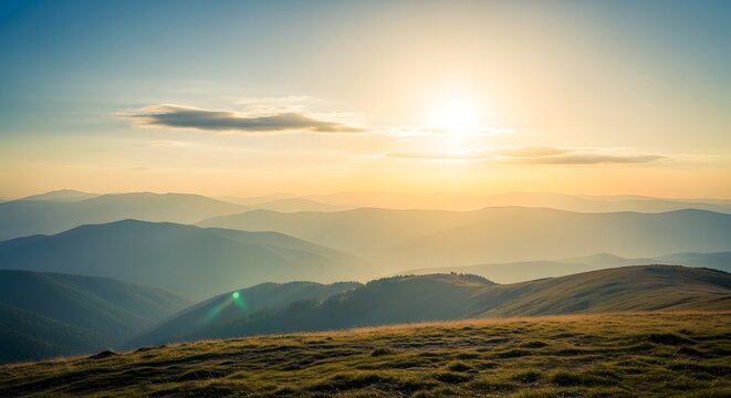 Panoramic view of rolling hills under a bright sunset with a clear sky and golden sunlight shining over the landscape with grassy foreground