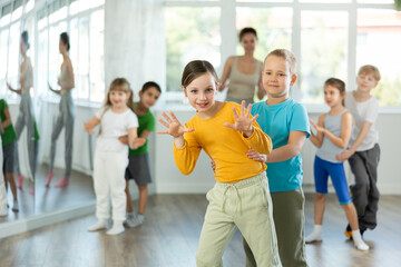 Group of children training movements of twist in dance studio with female tutor