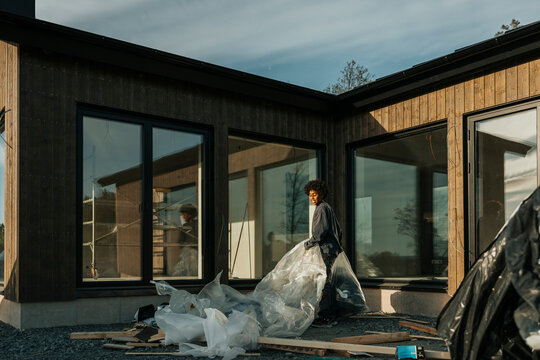 Boy picking up construction waste in trash bags outside house