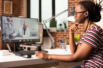 Self employed woman speaking with doctor on video call, discussing diagnosis and side effects while...