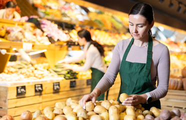 Female employee informs about arrival of ripe potato, advertises product. Assistant seller in...
