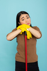 Portrait of tired asian female cleaner leaning on broomstick with sad expression. Young housekeeper...