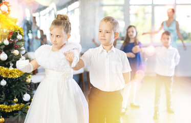 Naklejka premium Christmas ball - group of children in festive clothes dances a waltz around the New Year tree
