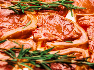 Premium quality marinated lamb loin chops and rosemary herb on white background. Uncooked raw meat...