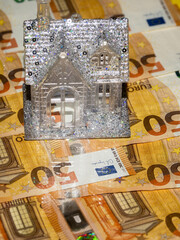 Premium glamourous house with glitter is standing on top of a flat surface covered cash money....