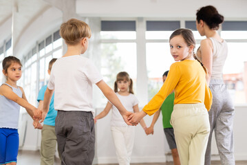 Fototapeta premium Boys and girls holding hands perform incendiary traditional roundelay folk dance during rehearsal in studio.