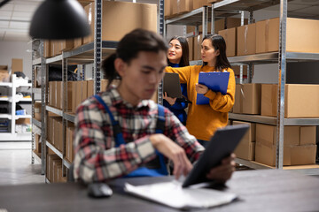Workers team manages product handling in a storage room with taped boxes. Local shipping services...