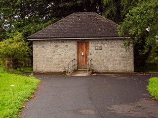 Old public rest room or toilet with sign man and woman in a forest park. The building looks...