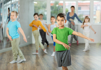During dance workshop, boy with team of young like-minded children learn to dance modern dances,...