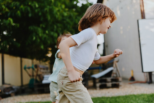 Active boy running in the backyard, enjoying playtime with friends in a bright, vibrant setting filled with greenery and sunlight.