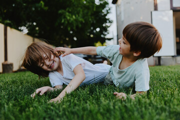 Joyful children playing outside on a sunny day, enjoying their time together on the green grass,...